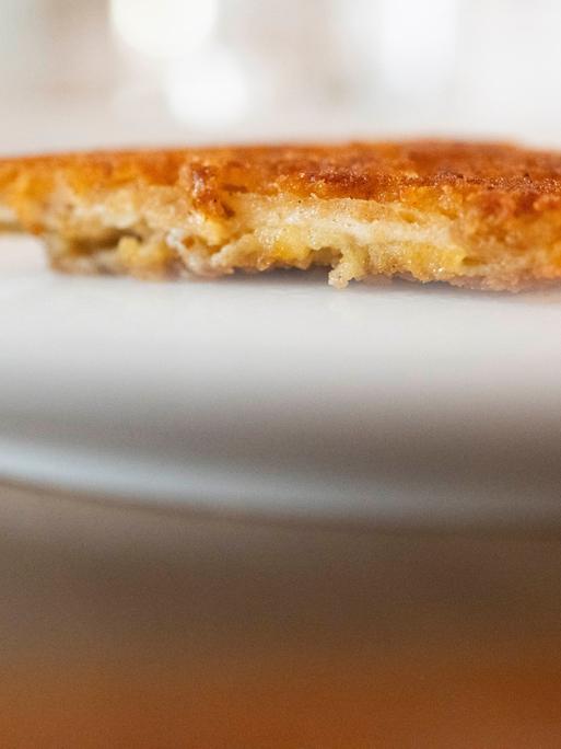 Ein veganes Schnitzel liegt auf einem Teller. Es sieht gut aus. Das Äußere ist offenbar goldfarben und knusprig, das Innere faserig und hell.