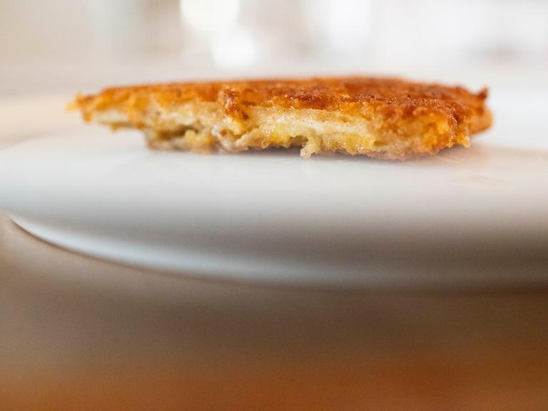 Ein veganes Schnitzel liegt auf einem Teller. Es sieht gut aus. Das Äußere ist offenbar goldfarben und knusprig, das Innere faserig und hell.