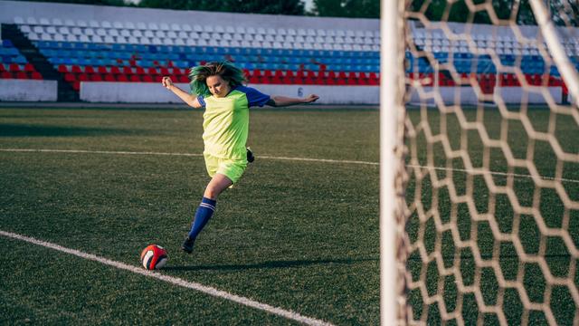 Eine Frau schießt gegen einen Fußball