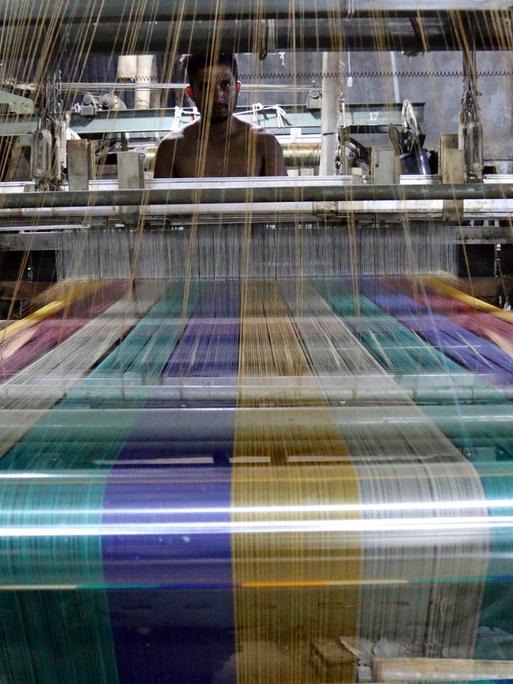 Ein Arbeiter an einem Webstuhl in einer Textilfabrik in Bangladesch