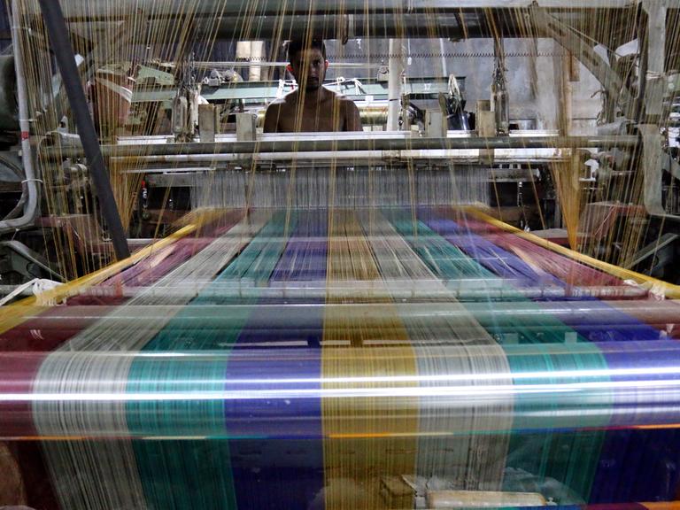 Ein Arbeiter an einem Webstuhl in einer Textilfabrik in Bangladesch