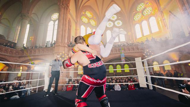 Wrestling-Veranstaltung des Vereins „enter – Junge Kulturregion Chemnitz“ // Wrestler auf Bühne mit Publikum außenherum in einer großen Halle, die wie eine ehemalige Kirche aussieht
