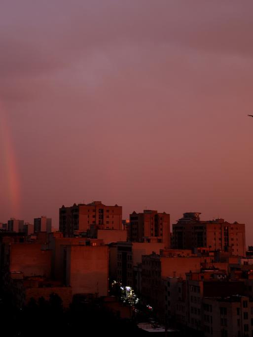 In der iranischen Hauptstadt Teheran geht gerade die Sonne auf. Über den Häusern der Stadt hängt eine dichte, rosafarbene Wolkendecke. Das Bild wurde am 10.12.25 aufgenommen.