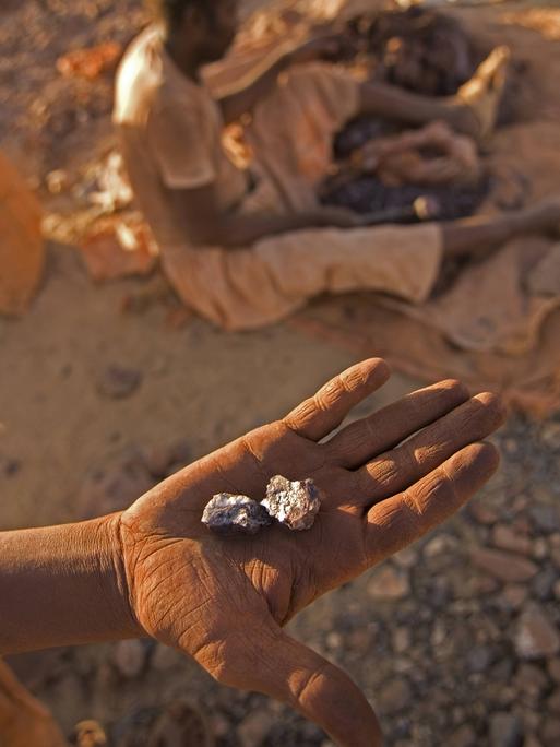 Illegale Goldmine im Sudan: Eine Hand zeigt ein Stück Stein, das Gold enthält.