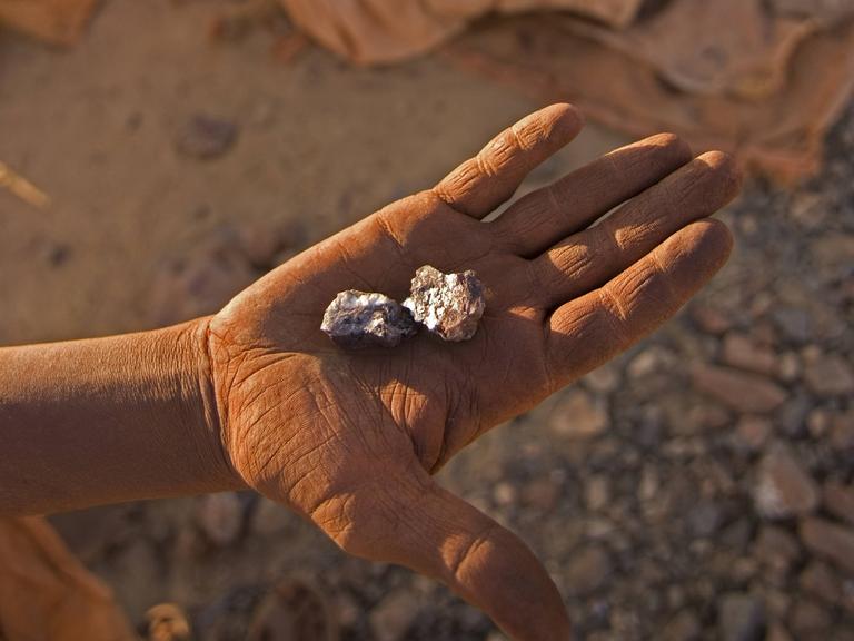 Illegale Goldmine im Sudan: Eine Hand zeigt ein Stück Stein, das Gold enthält.