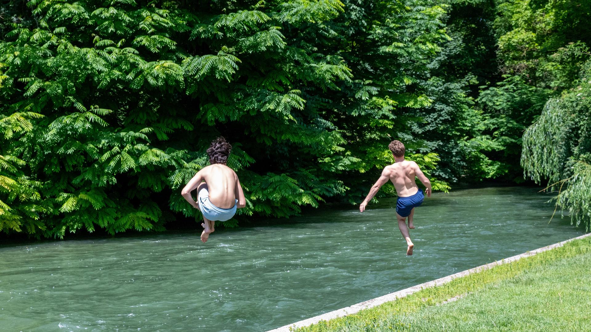 Zwei junge Männer springen zur Abkühlung in den Eisbach