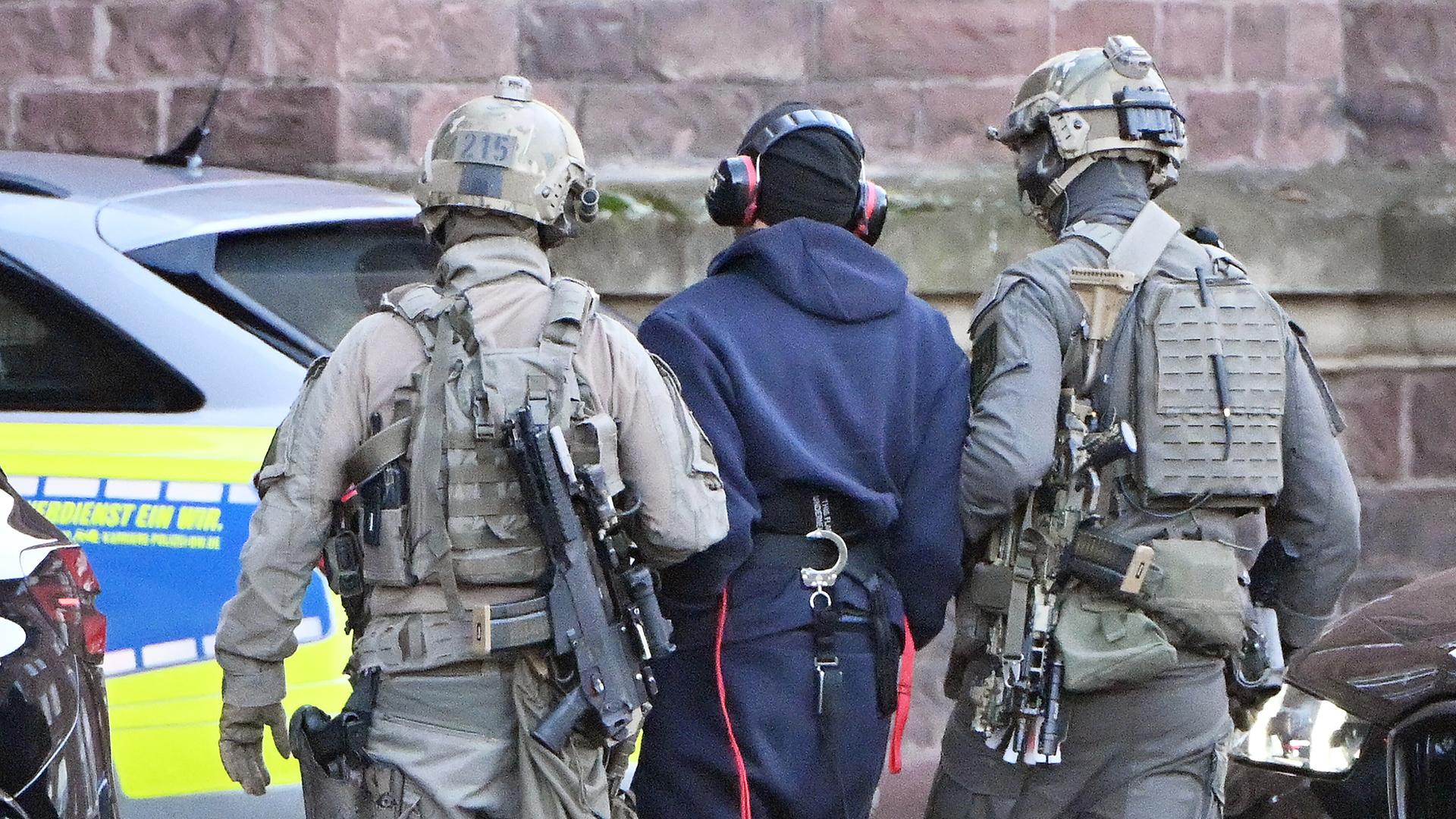 Eine Person wird von einem Hubschrauber zu einer Wagenkolonne geführt. 