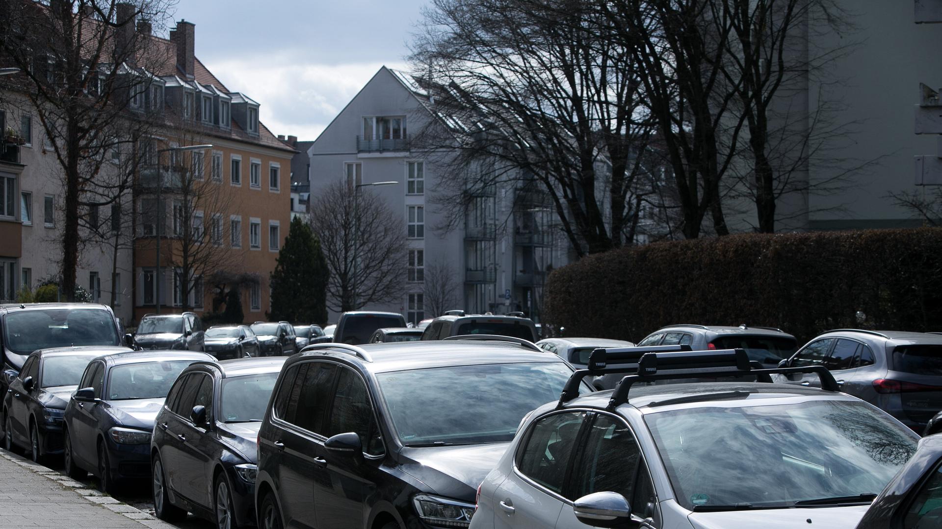 In einer Straße stehen dicht geparkt an beiden Straßenseiten sehr viele Autos.