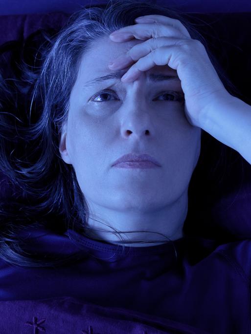 Frau liegt nachts wach grübelnd im Bett. Frau liegt nachts wach grübelnd im Bett.