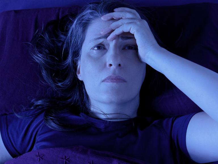 Frau liegt nachts wach grübelnd im Bett. Frau liegt nachts wach grübelnd im Bett.