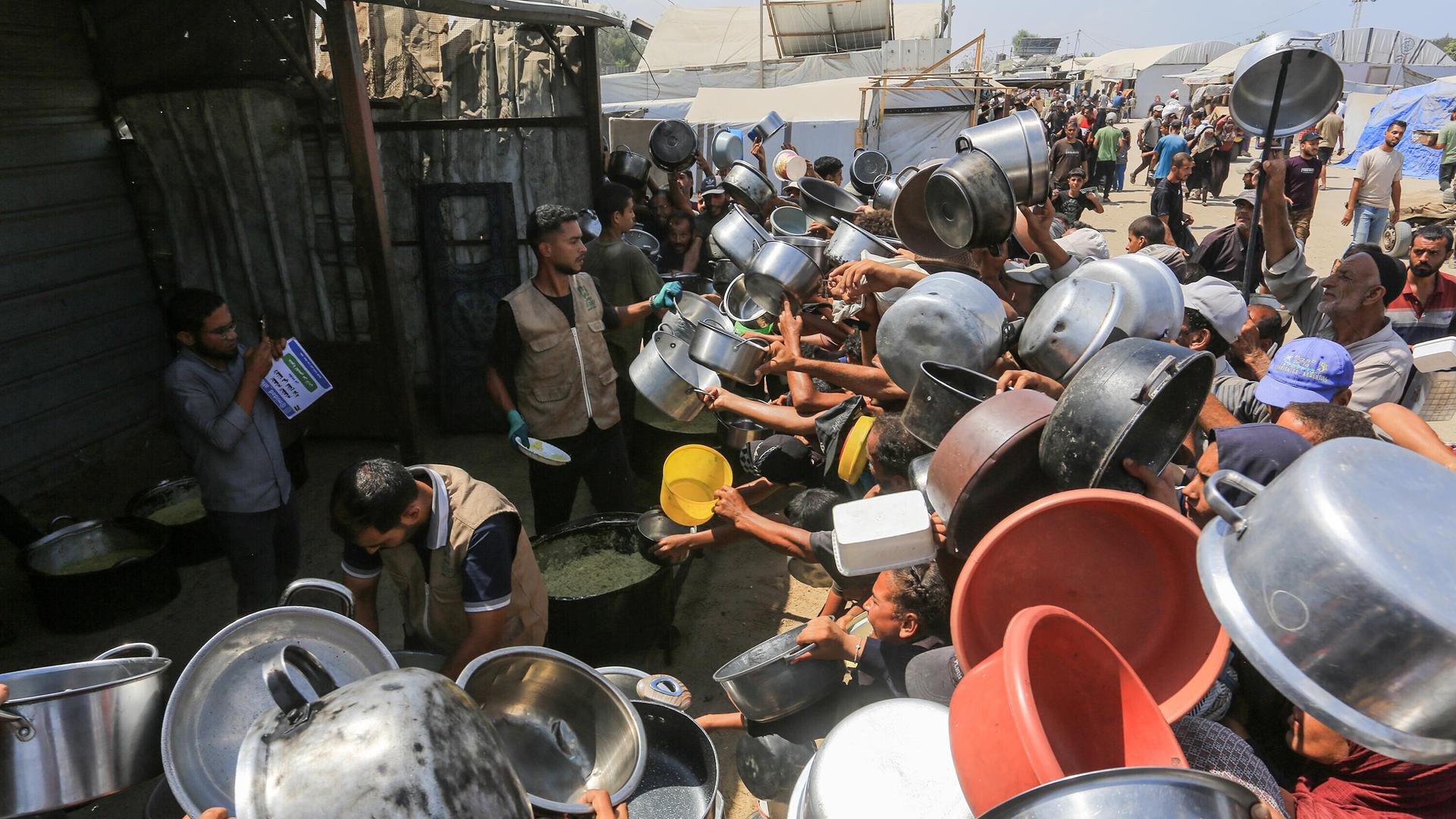 Palästinenser, darunter auch Kinder, die aufgrund der Blockade Israels und der anhaltenden Angriffe auf den Gazastreifen Schwierigkeiten haben, sich mit Lebensmitteln zu versorgen, stehen am 21. August 2025 in Khan Yunis im Gazastreifen in der Region…