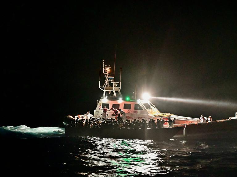 Mittelmeer: Schiffe der Italienischen Küstenwache evakuieren ein Boot mit Flüchtenden Mittelmeer: Schiffe der Italienischen Küstenwache evakuieren ein Boot mit Flüchtenden