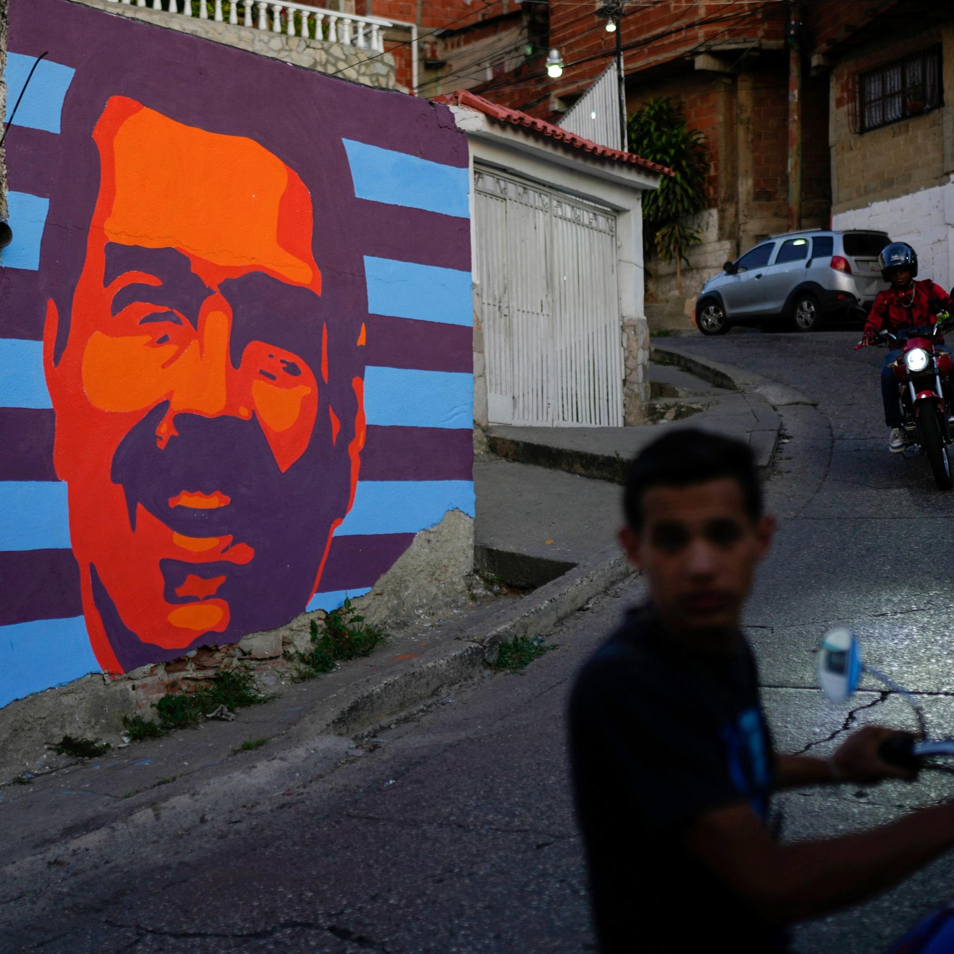 Zwei Mopedfahrer fahren in Caracas an einem Wahlkampf-Mural von Nicolás Maduro vorbei (Venezuela,17.07.2024)