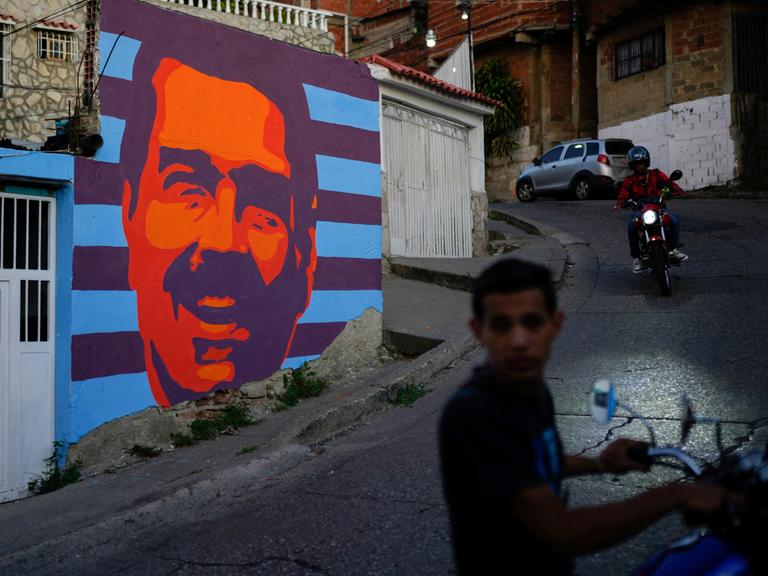 Zwei Mopedfahrer fahren in Caracas an einem Wahlkampf-Mural von Nicolás Maduro vorbei (Venezuela,17.07.2024)