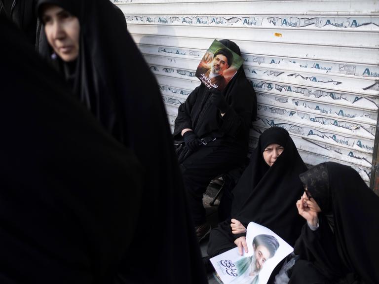 Eine verschleierte Iranerin lehnt sich während einer Jubeldemonstration für Mojtaba Khamenei Anfang März 2026 an die Jalousie eines Geschäfts.