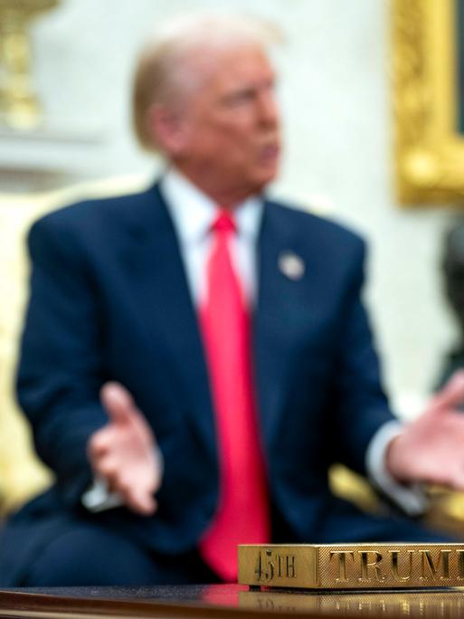Vergoldeter Untersetzer mit der Aufschrift "45th" und "Trump". Im Hintergrund US-präsident Donald Trump Vergoldeter Untersetzer mit der Aufschrift "45th" und "Trump". Im Hintergrund US-präsident Donald Trump