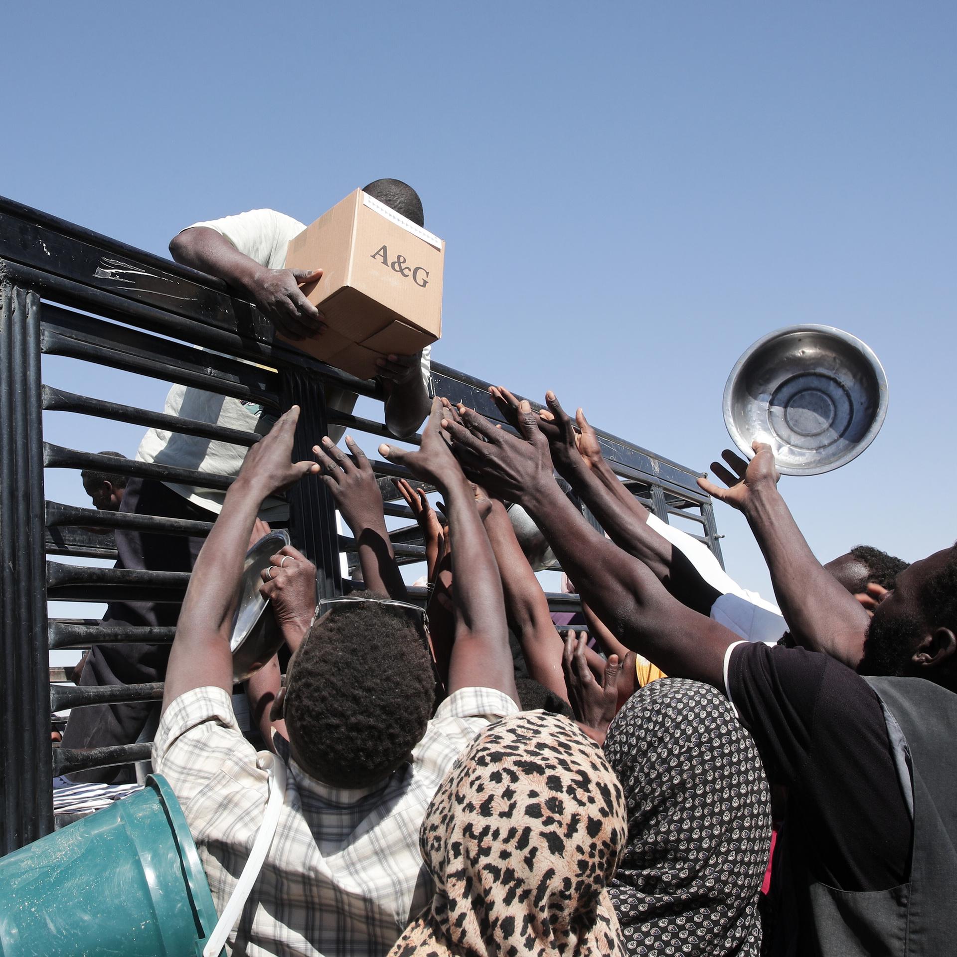 Im Sudan versammeln sich Menschen vor einem Lastwagen von humanitären Helfern.