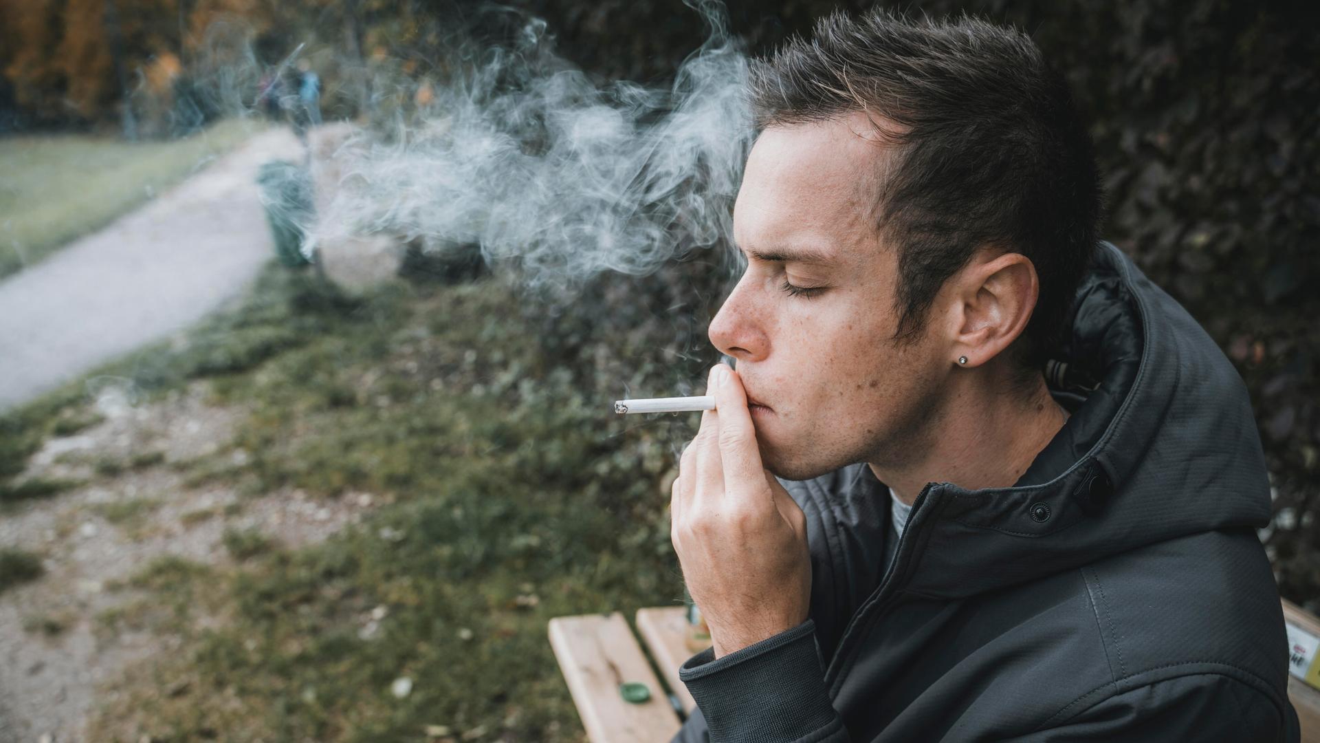Junger Typ zieht an einer brennenden Zigarette