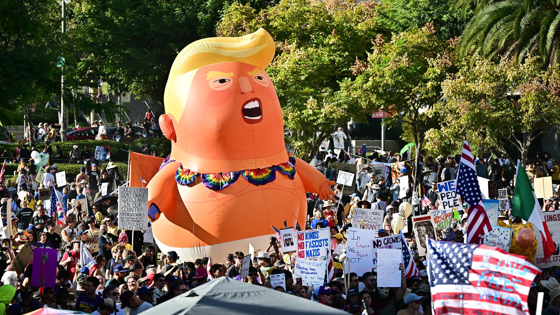 Eine No-Kings-Demonstration mit Plakaten und einer großen aufblasbaren Puppe in Form von Donald Trump Eine No-Kings-Demonstration mit Plakaten und einer großen aufblasbaren Puppe in Form von Donald Trump