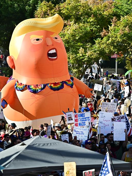 Eine No-Kings-Demonstration mit Plakaten und einer großen aufblasbaren Puppe in Form von Donald Trump Eine No-Kings-Demonstration mit Plakaten und einer großen aufblasbaren Puppe in Form von Donald Trump
