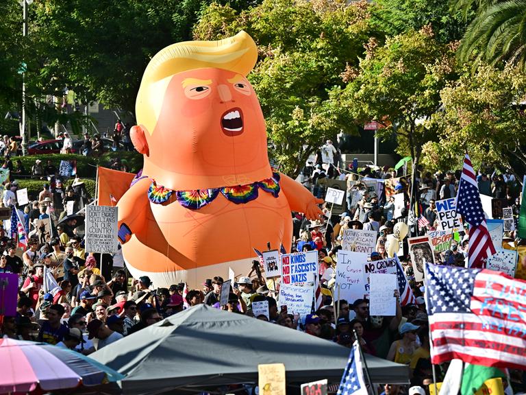 Eine No-Kings-Demonstration mit Plakaten und einer großen aufblasbaren Puppe in Form von Donald Trump Eine No-Kings-Demonstration mit Plakaten und einer großen aufblasbaren Puppe in Form von Donald Trump