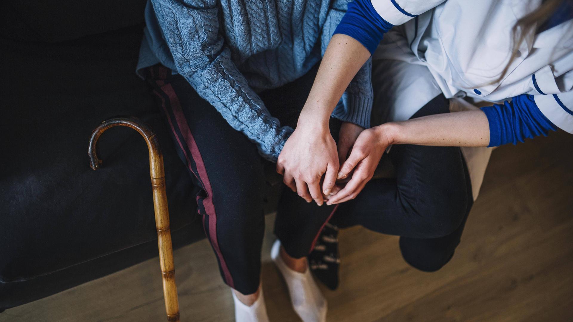 Symbolbild Pflege Eine Krankenschwester hält die Hände einer älteren Frau.