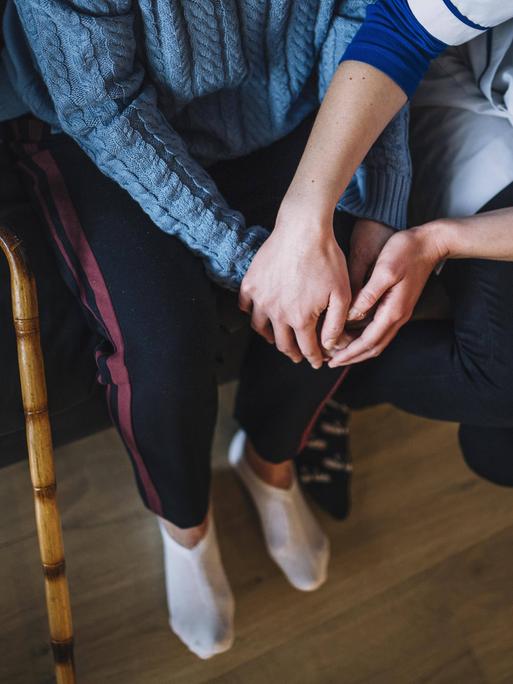 Symbolbild Pflege Eine Krankenschwester hält die Hände einer älteren Frau.