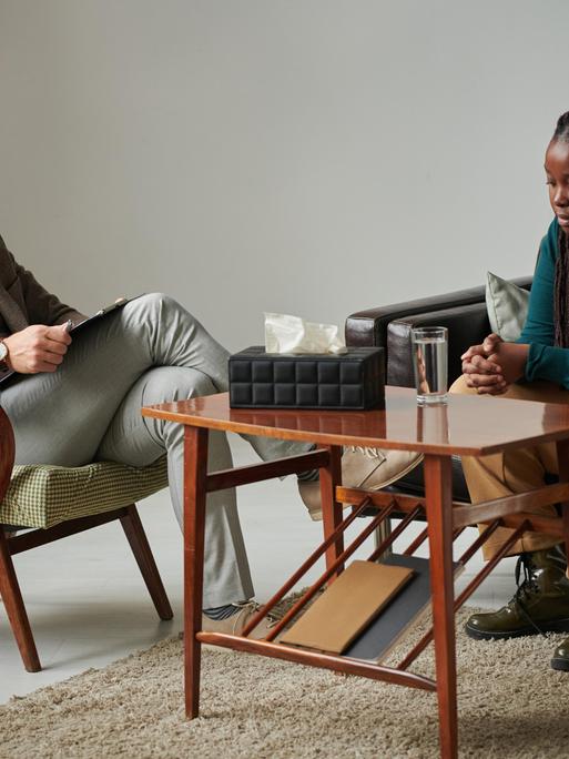 Eine Frau befindet sich in einer Sitzung mit einem Therapeuten Eine Frau befindet sich in einer Sitzung mit einem Therapeuten