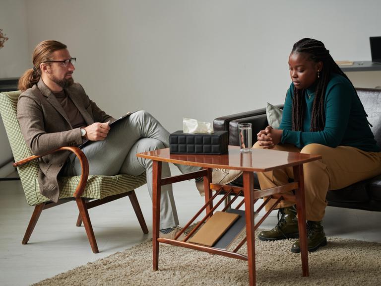 Eine Frau befindet sich in einer Sitzung mit einem Therapeuten Eine Frau befindet sich in einer Sitzung mit einem Therapeuten