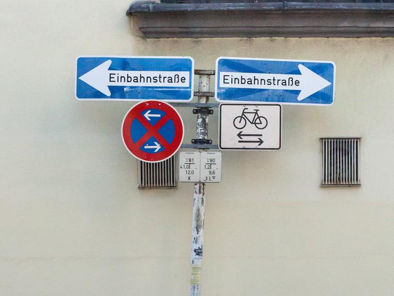 Ein Fahrrad parkt unter sich scheinbar widersprechenden Verkehrsschildern