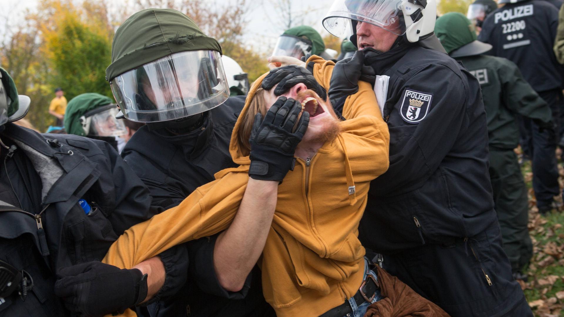 Polizisten wenden bei einem Mann einen schmerzhaften Kotrollgriff an.
