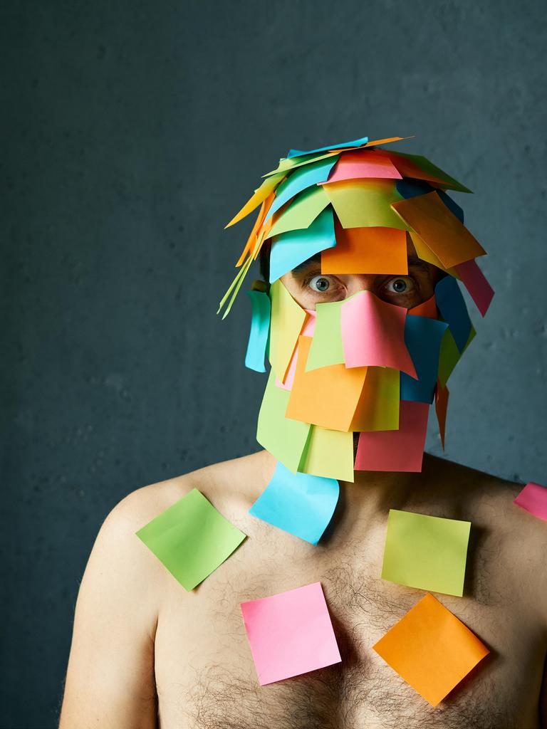 Ein Mann hat viele Post-its-Notes im Gesicht und auf den Schultern kleben und schaut gestresst