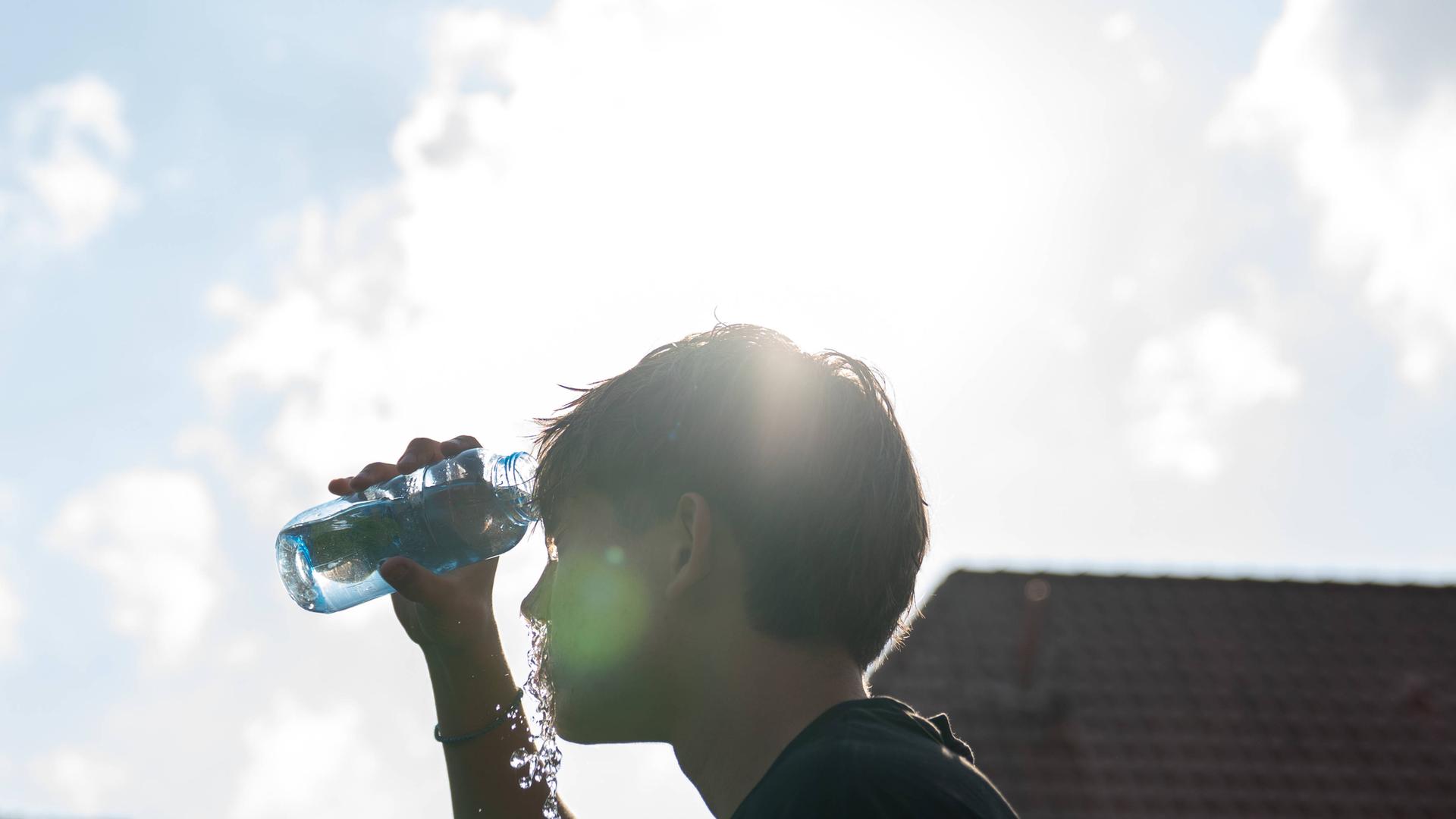 Ein junger Mann kühlt sich an einem heißen Sommertag mit Wasser ab. Ein junger Mann kühlt sich an einem heißen Sommertag mit Wasser ab.