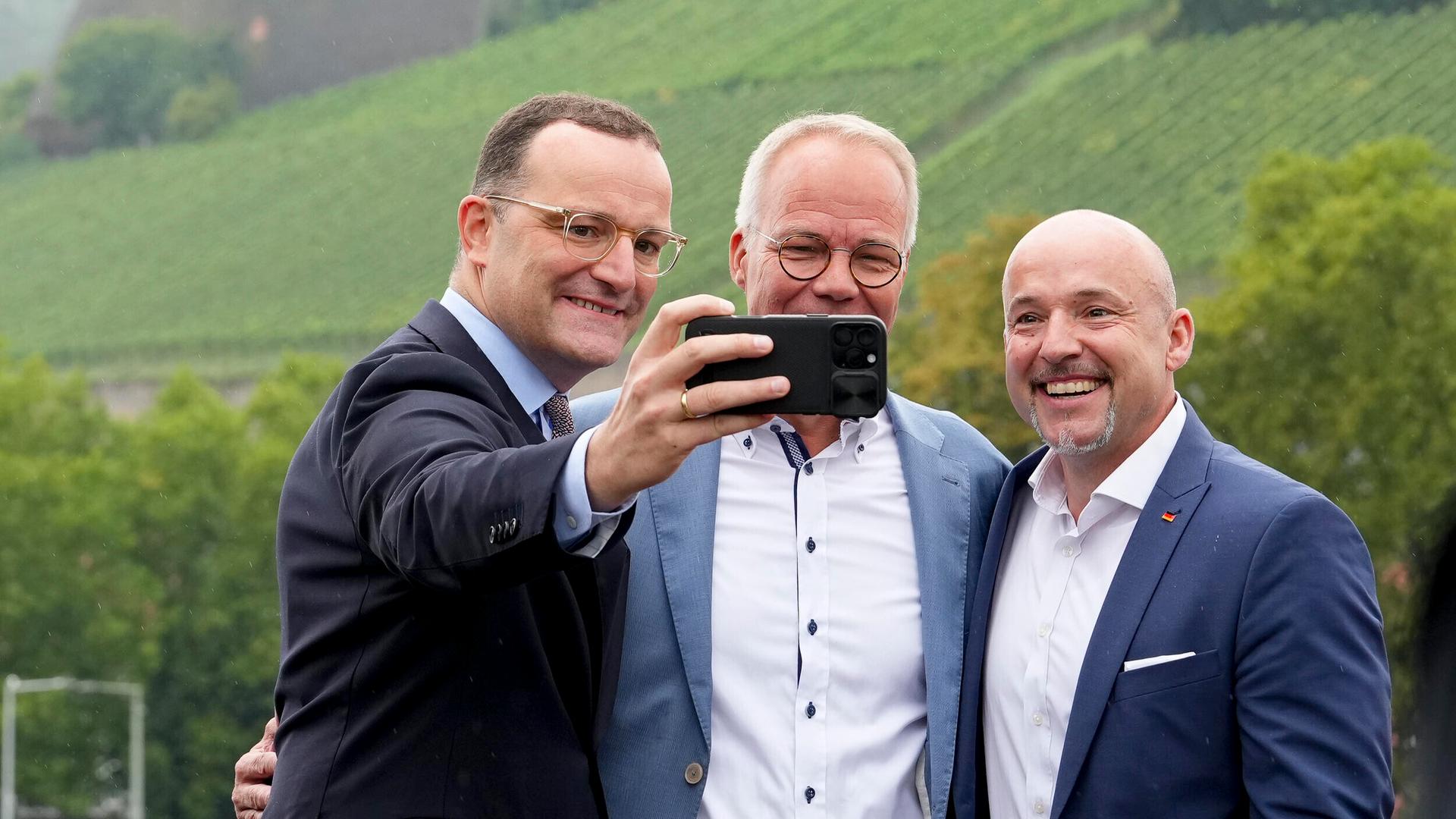 Jens Spahn (CDU) macht ein Selfie von sich, Alexander Hoffmann (CSU) und Matthias Miersch (SPD) auf der alten Mainbrücke in Würzburg (28.08.2025)