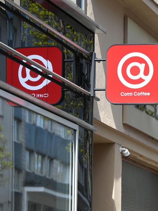 Schild der Kaffeekette Cotti Coffee an einer Hausfassade - ein weißes @-Zeichen auf rotem Grund Schild der Kaffeekette Cotti Coffee an einer Hausfassade - ein weißes @-Zeichen auf rotem Grund