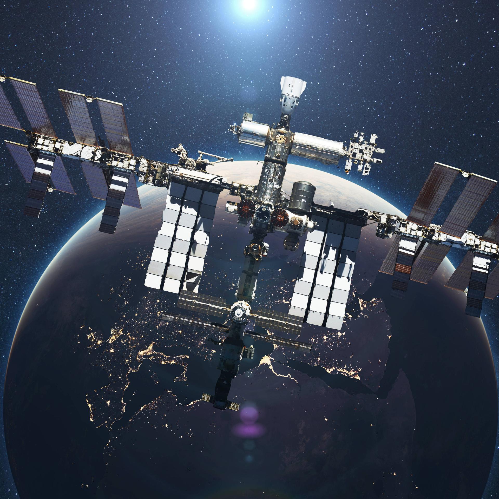Die ISS fliegt vor dem Hintergrund des blauen Planeten Erde mit dem Licht der Sonne.