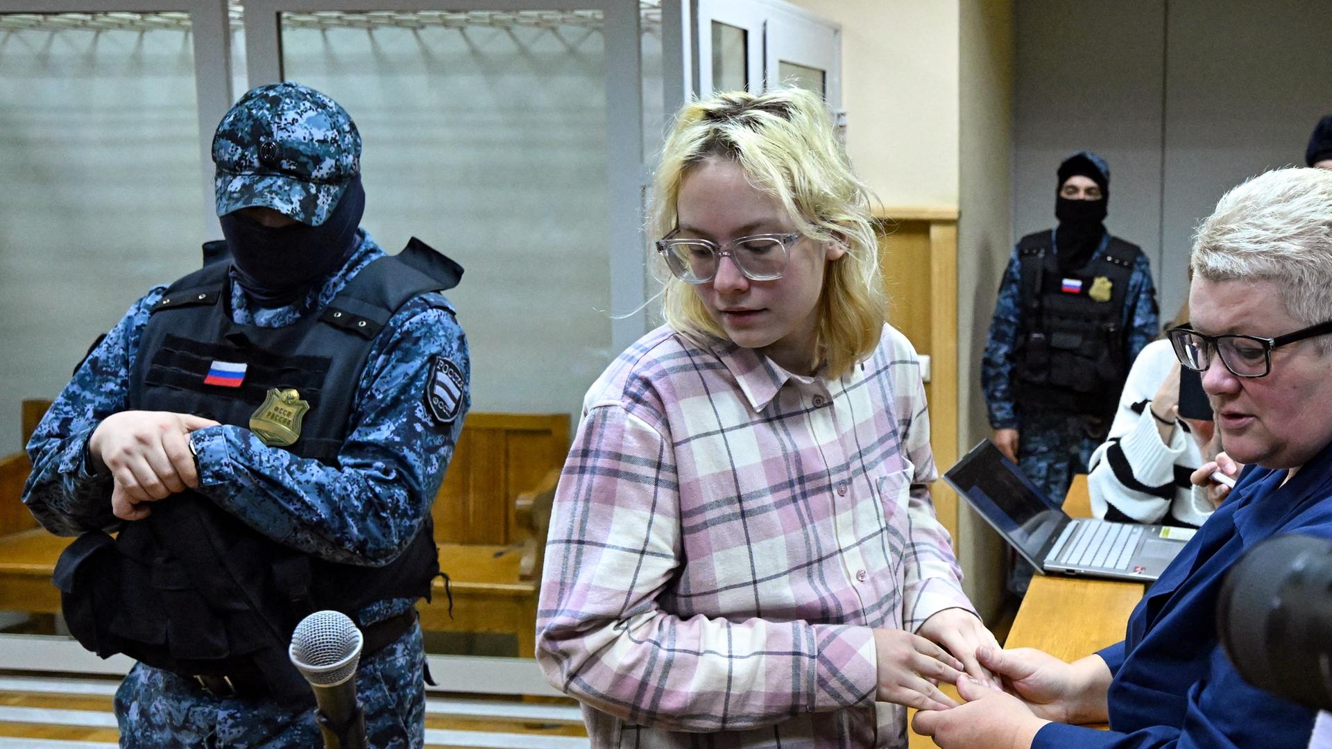 Diana Loginowa vor Gericht in St. Petersburg, neben ihr steht ein vermummter russischer Polizist (11.11.2025) Diana Loginowa vor Gericht in St. Petersburg, neben ihr steht ein vermummter russischer Polizist (11.11.2025)
