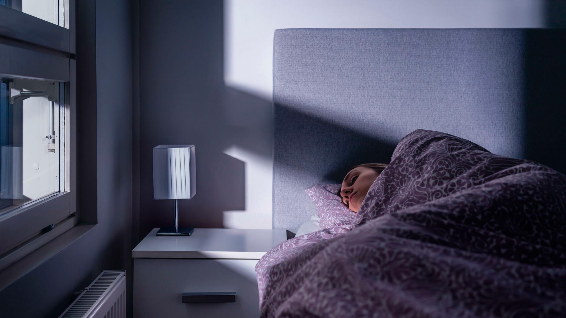 Eine Frau liegt in einem Bett und schläft. Eine Frau liegt in einem Bett und schläft.