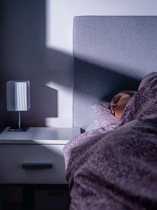 Eine Frau liegt in einem Bett und schläft Eine Frau liegt in einem Bett und schläft