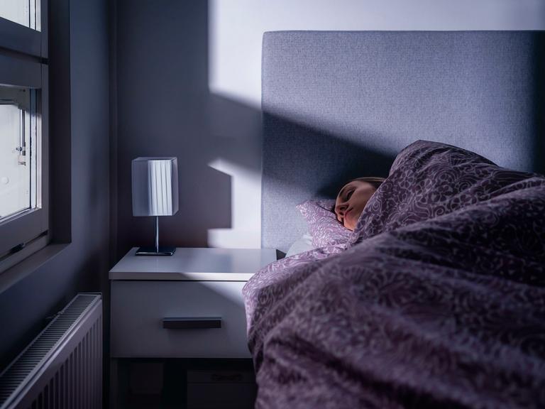 Eine Frau liegt in einem Bett und schläft Eine Frau liegt in einem Bett und schläft