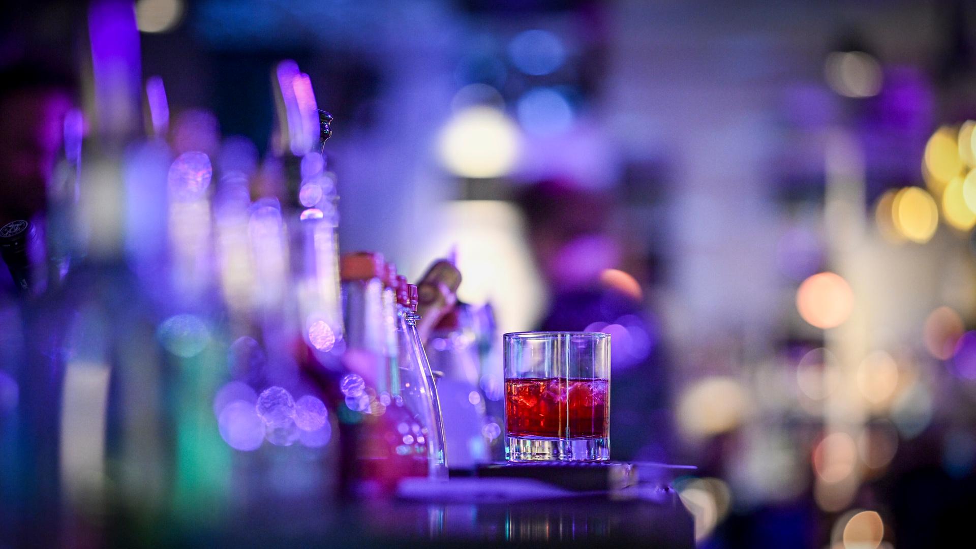 Ein einzelnes Glas mit einem Cocktail steht auf einem Tresen Ein einzelnes Glas mit einem Cocktail steht auf einem Tresen