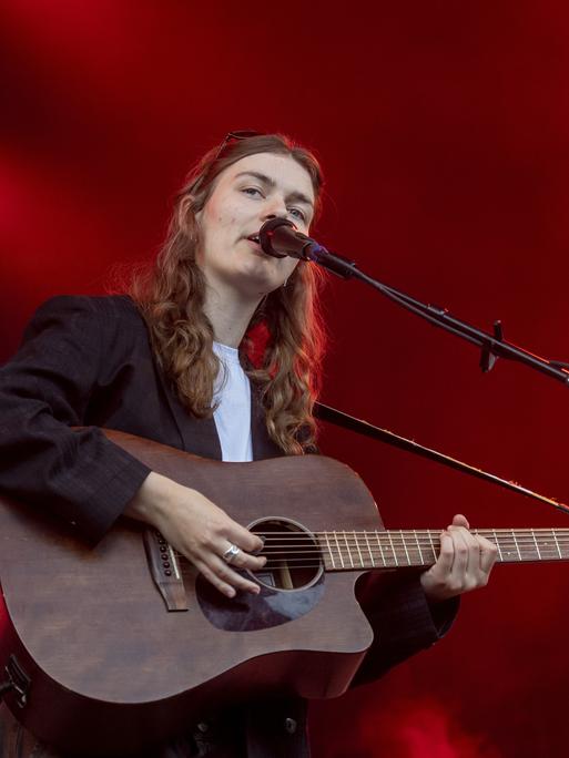 Musikerin Philine Sonny steht bei einem Festival auf der Bühne. Sie singt in ein Mikrofon und spielt dabei ihre Gitarre. Musikerin Philine Sonny steht bei einem Festival auf der Bühne. Sie singt in ein Mikrofon und spielt dabei ihre Gitarre.