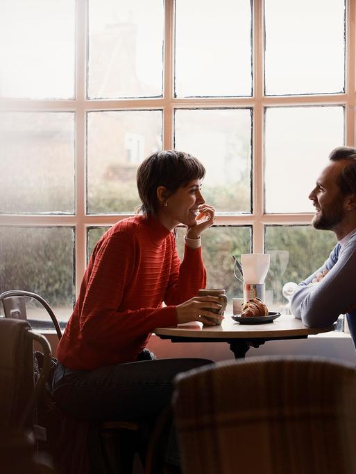 Eine Frau und ein Mann sitzen in einem Café und unterhalten sich
