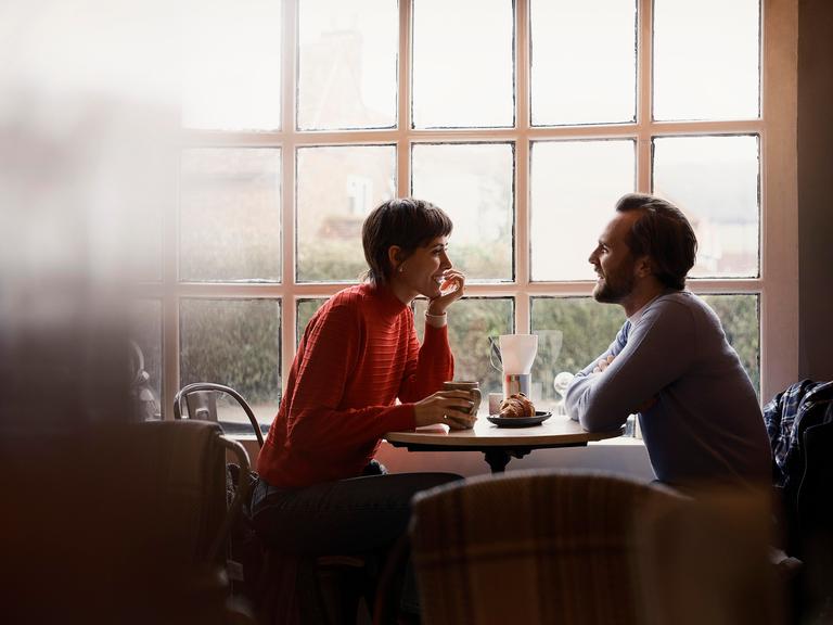 Eine Frau und ein Mann sitzen in einem Café und unterhalten sich