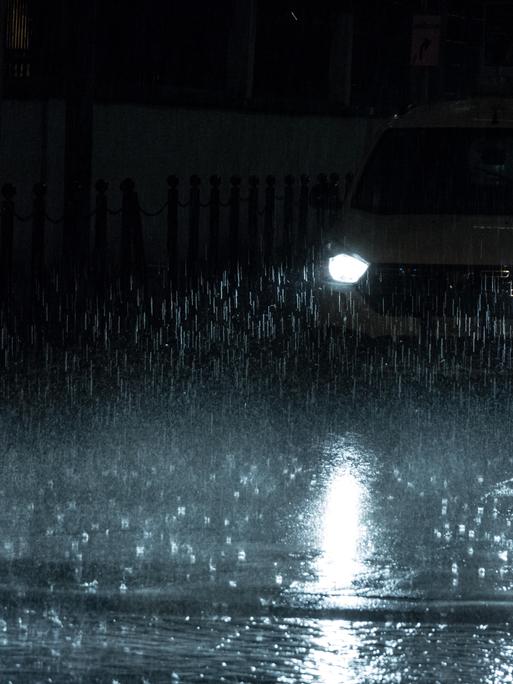 Scheinwerfer eines Autos bei Nacht und im Regen.