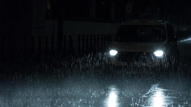 Scheinwerfer eines Autos bei Nacht und im Regen.