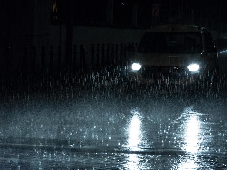 Scheinwerfer eines Autos bei Nacht und im Regen.