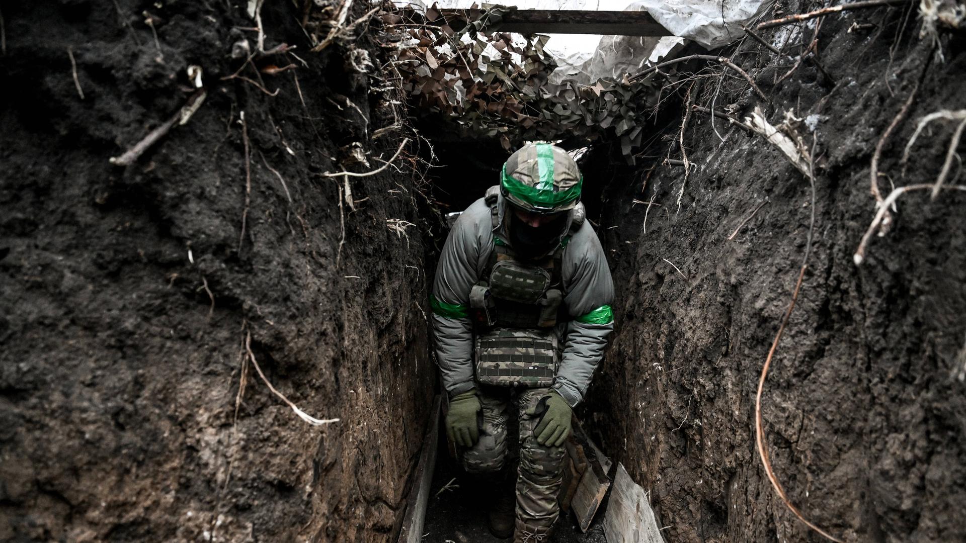 Ein ukrainischer Soldat läuft gebeugt durch einen Schützengraben.