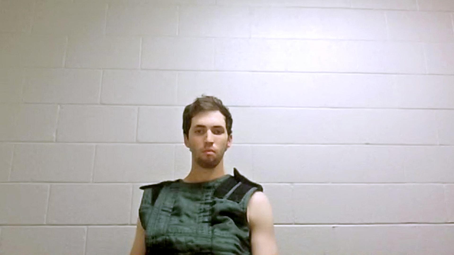 Tyler Robinson sitzt vor einer weißen gemauerten Wand. Sein Blick geht in die Leere. Tyler Robinson sitzt vor einer weißen gemauerten Wand. Sein Blick geht in die Leere.