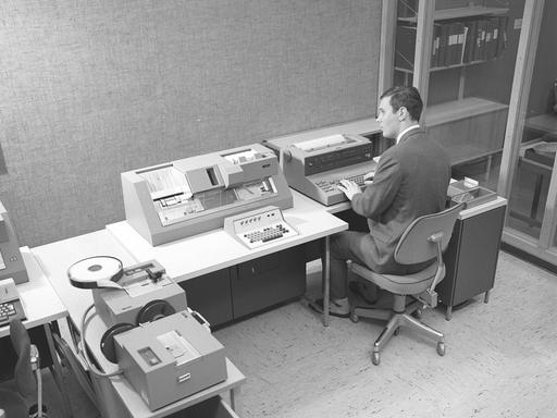 Schwarz-weiß Foto eines Mannes, der in den 1960er Jahren an einem Teil des Computers IBM System 360 arbeitet.